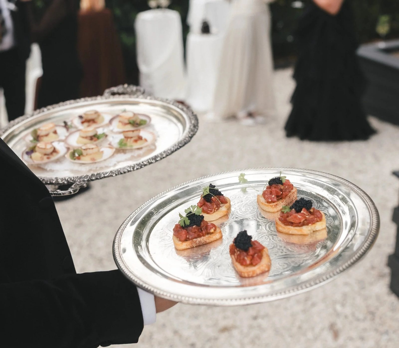 Canap&eacute;s on a silver tray among black-tie guests