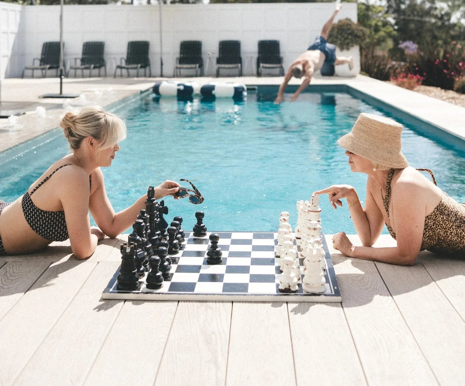 Two guests playing giant chess beside the pool the morning after