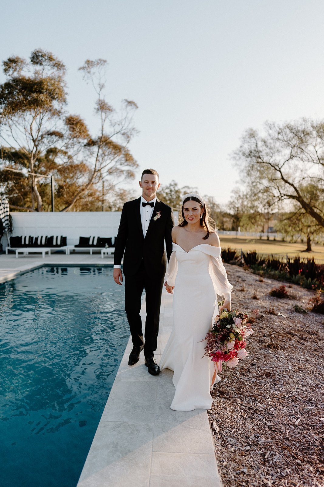 A couple walking beside the pool at golden hour