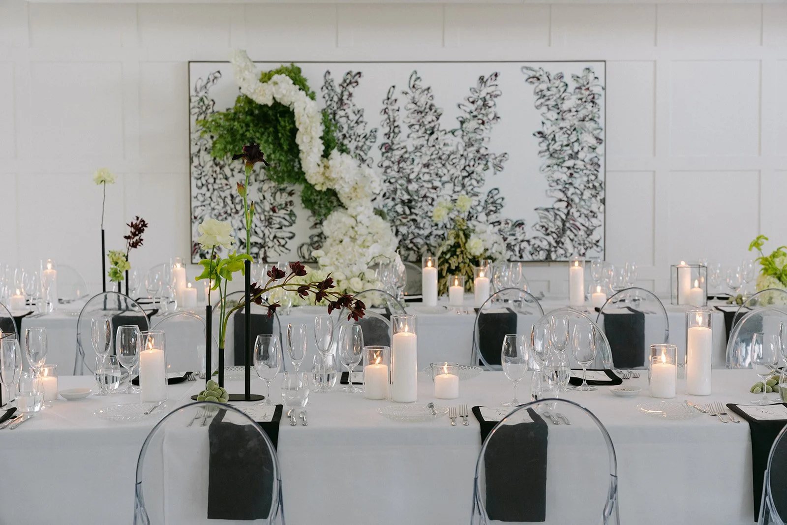A reception table with white florals and candles against the panelled wall